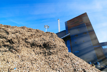 bio power plant with storage of wooden fuel against blue sky