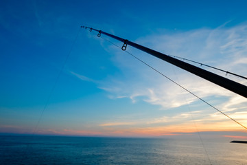 The silhouette of fishing poles under dramatic sunset and beautiful sea