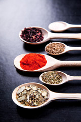 spice in wood spoon on a black background. food