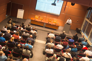 Speaker giving a talk in conference hall at business event. Audience at the conference hall....