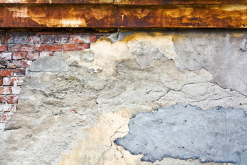 Grunge texture of old wall. Cracked stucco crumbles. Rusty iron roof.