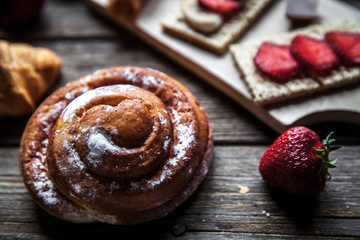 delicious breakfast with strawberries and sweet bun on wooden background. Fruit, food, chocolate