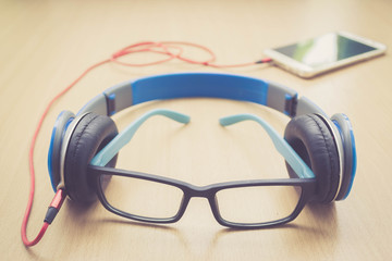 glasses headphone and smartphone on wood floor