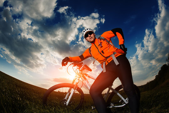 biker in orange jersey riding on green summer field © Aleksey