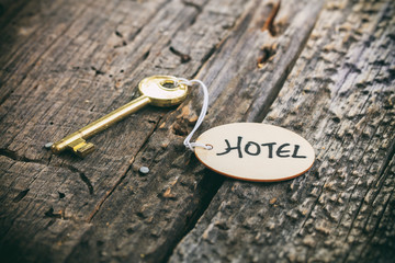 Round wooden tag with "Hotel" text on a key,wooden surface