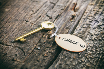 Round wooden tag with "Hotel" text on a key, on wooden surface