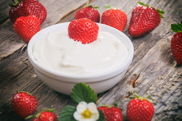 Creamy yogurt with strawberries, on wooden surface.
