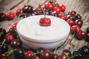 Creamy yogurt with cherries, on wooden surface.