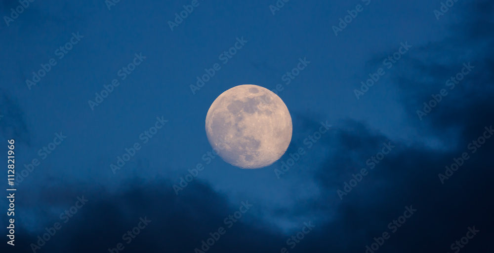 Wall mural full glowing moon closeup on blue sky and dark misty clouds