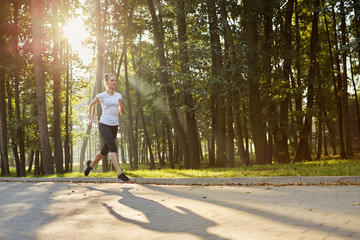 Fototapeta premium Attractive young woman running in park during sunny morning