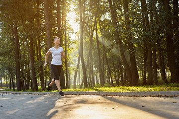 Fototapeta premium young woman running in park during sunny morning