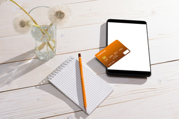Credit card, tablet and notebook with pencil on the table