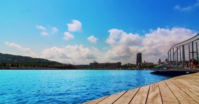 Barcelona port. Port Vell - marina in Barcelona, Spain. Timelapse of clouds over sea marina. Blue sea and sky. Travel destination. Time lapse of sea harbour in Barcelona city. Wooden pier in sea port