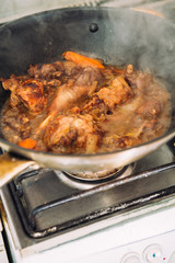 chicken in sauce with carrots on a pan closeup