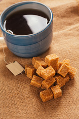 blue cup of tea and lump sugar on sacking background