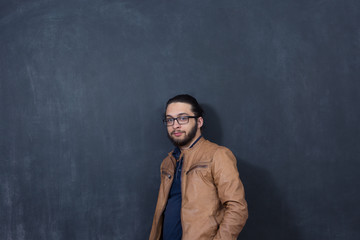 Attractive young man against blackboard.