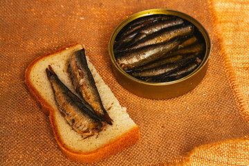 open can and sandwich with of sprats on sackcloth background