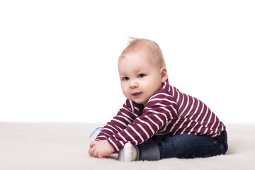 cute baby boy with big hazel eyes sitting on a blanket, smiling and played. child on a white background, isolated. happy family concept