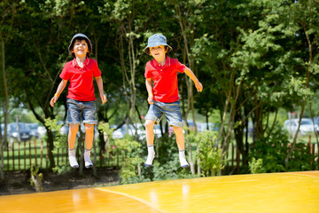 Obraz premium Two sweet children, boy brothers, jumping on a big trampoline