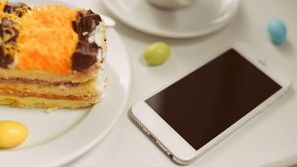 Closeup flat lay of coffee cup, smart phone and cakes on wood background. Top view