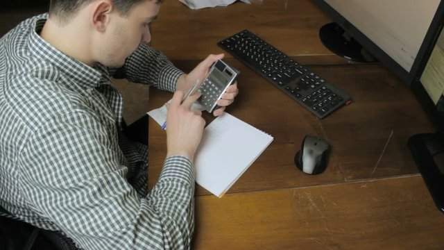 Man counting on a calculator records from notepad