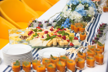 Beautifully decorated catering banquet table with different food snacks and appetizers with sandwich, caviar, fresh fruits on corporate christmas birthday kids party event or wedding celebration