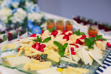 Beautifully decorated catering banquet table with different food snacks and appetizers with sandwich, caviar, fresh fruits on corporate christmas birthday kids party event or wedding celebration