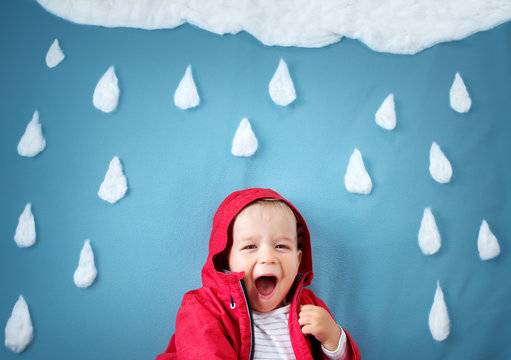 Little boy on blue background in coat with drop shapes