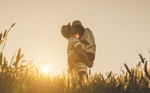 Young couple kissing on the background of a sunset in the wheat field