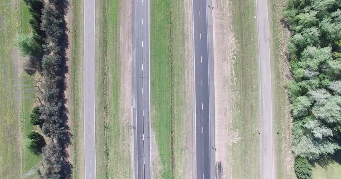 Top aerial scene of highway on the field. Trucks, motorcycle and cars movement is registered on the road. Comera stays still. 