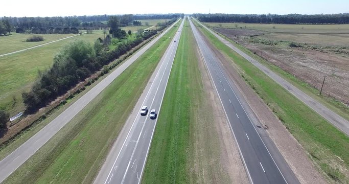 Aerial drone scene of highway in the countryside. Camera moves along the road. Cars and trucks circulation is registered. Traffic movement in rural areas.