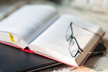 Books with a pair of glasses and computer laptop on bedroom