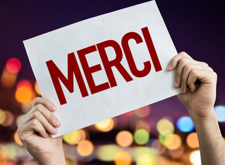 Thank You (in French) placard with night lights on background