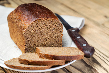 Loaf of sliced ​​brown bread in bowl on wooden table