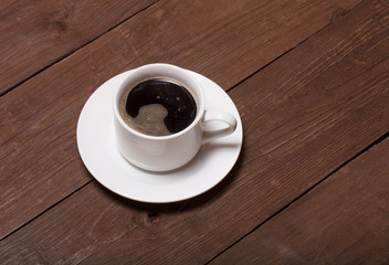 White cup of coffee on old wooden table