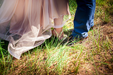 Fototapeta na wymiar Feet of the bride and groom in the green grass