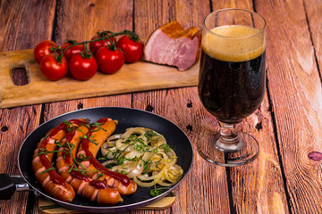 Tall glass with dark beer with fried sausages