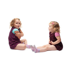 Couple of young little girls sitting over isolated white background