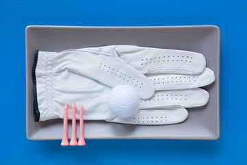 Gray ceramic dish with golf glove on over blue  background