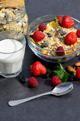Muesli with milk, nuts and berries for breakfast diet on a dark background