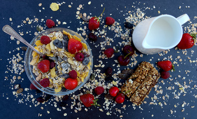 Muesli with milk, nuts and berries for breakfast diet on a dark background