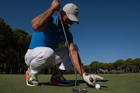 man's hand putting golf ball in hole