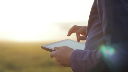 work and play on the tablet at sunset in the park in the summer, close-up
