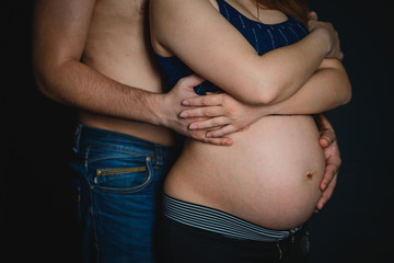 Man holding pregnant woman's stomach from behind