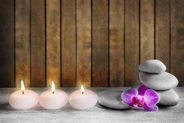 Fototapeta na wymiar White spa stones with candles on wooden background