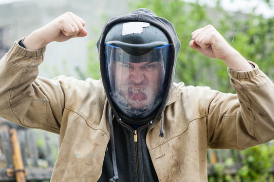 A man in a helmet bares his teeth and raised his hands clenched