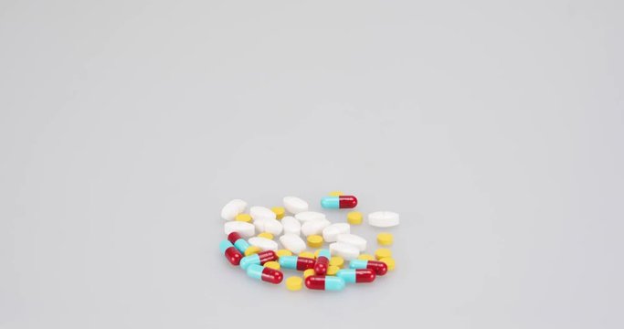 Colorful pills and capsules with golden coins time lapse