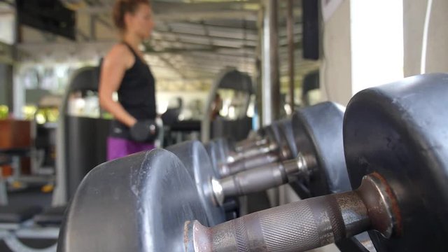Sportive Woman Lifting Dumbbells for a Power Workout at Gym