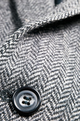 Button on a grey wool jacket.
Close up image of a single button on a grey wool jacket.