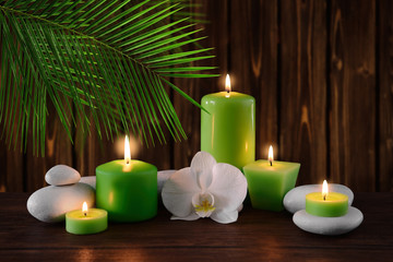 Spa stones with burning candles and flowers on wooden background